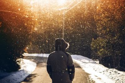 穿着连帽衫的人站在道路中间，正在下雪